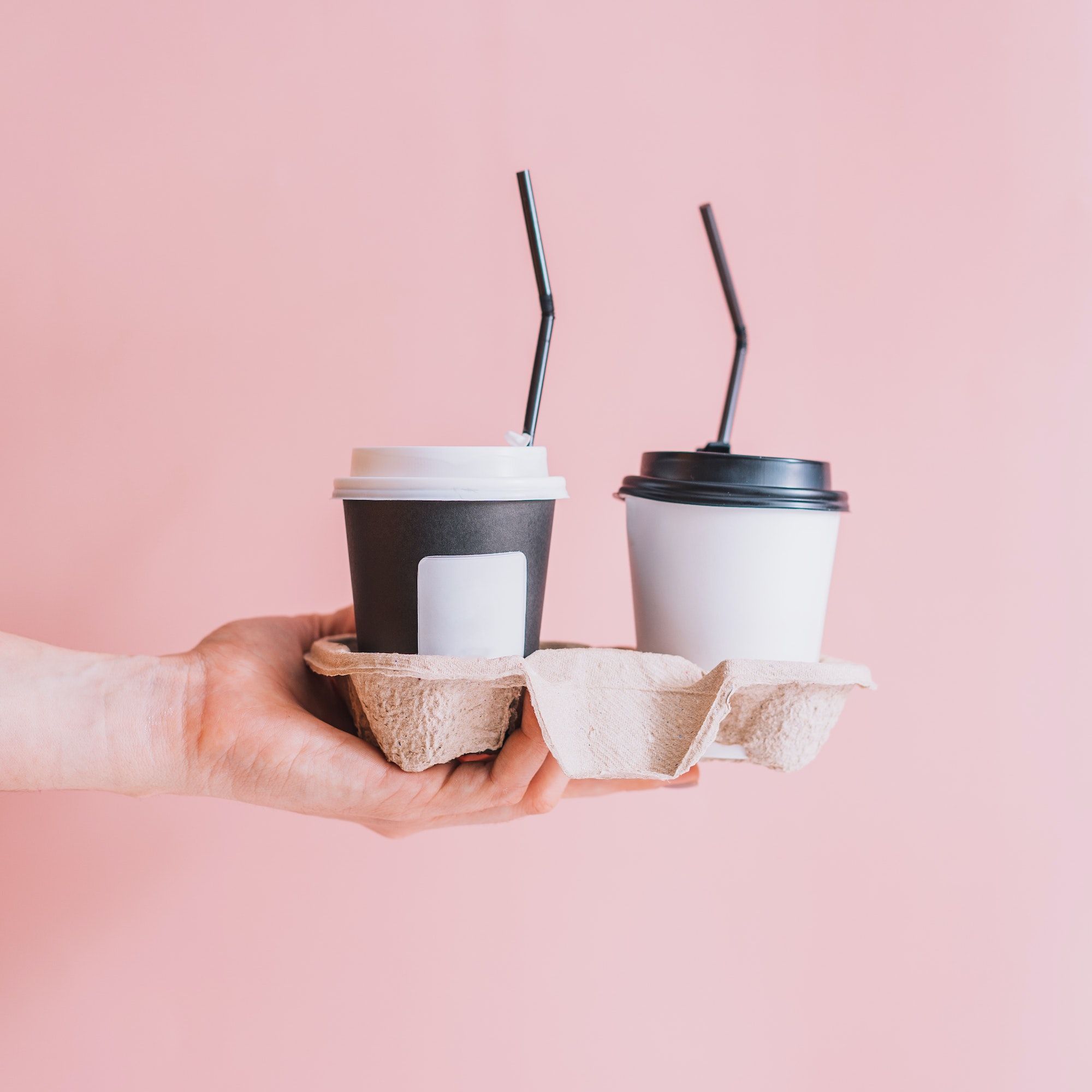 Thermos Cup with straw on trays in hand against pink background