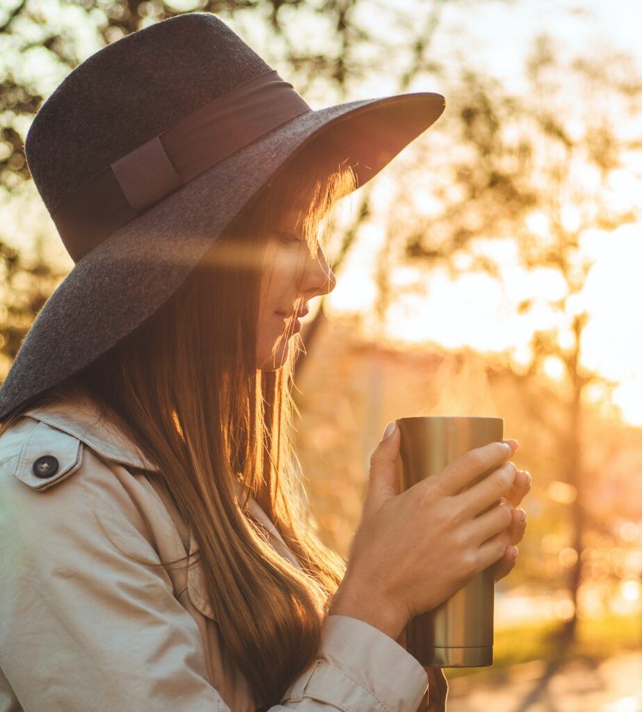 Young woman in a hat with thermos thermo cup